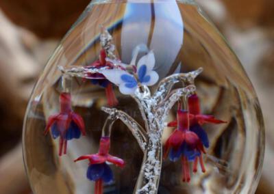 urnvan-glas-met fuchsia-bloemen-en-vlinder-waar-crematie-as-vast-in-glas-is-geblazen