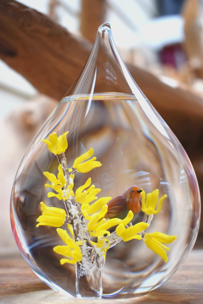 crematie-as-in-glas-urn-met-roodborstje-en-gele-bloemen